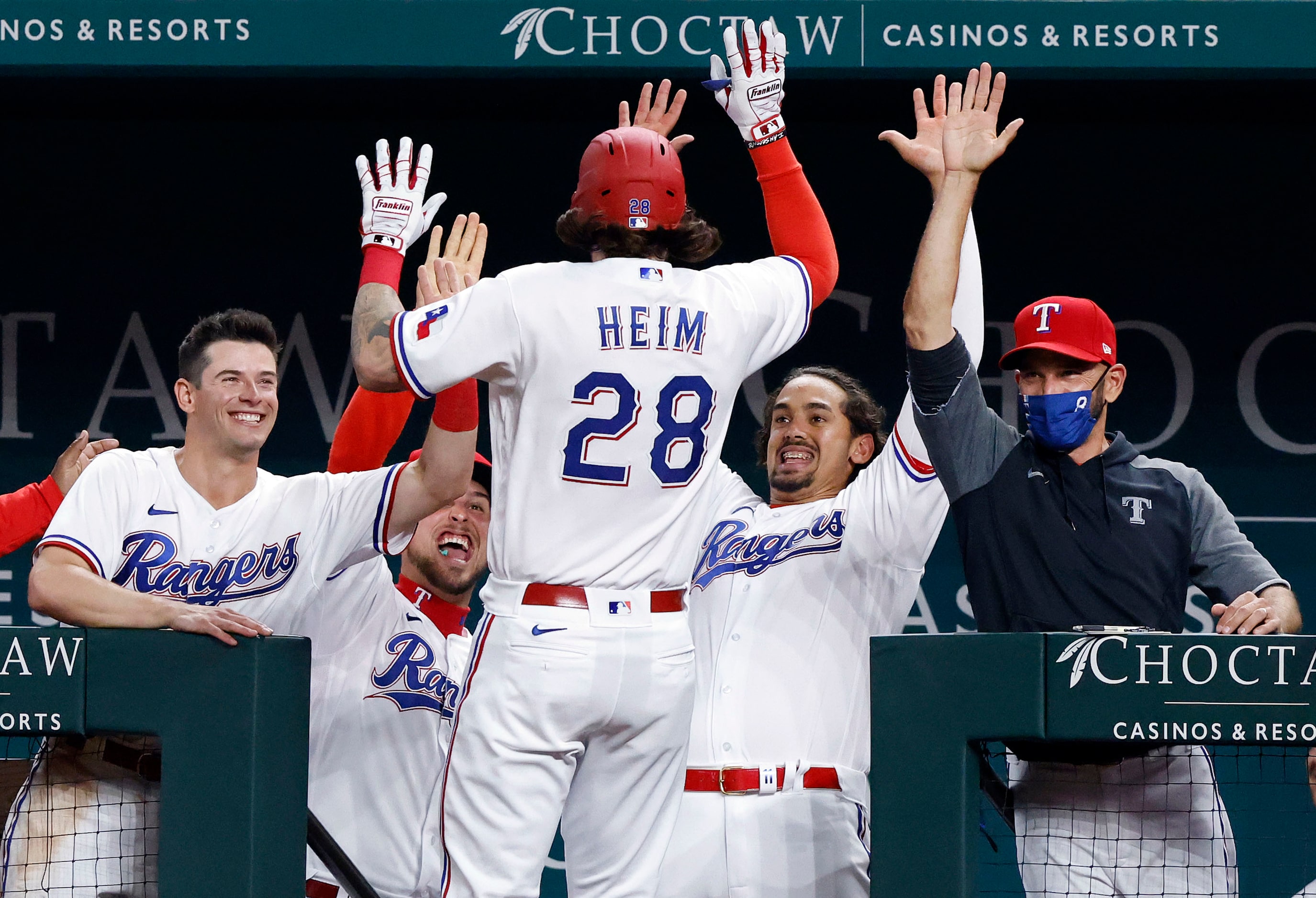 Texas Rangers Jonah Heim (28) is congratulated by manager Chris Woodward (right) and his...