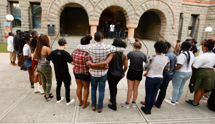 Protesters link arms in solidarity during a prayer at the end of the "Finish the March: A...