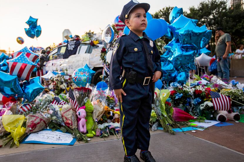 Diego Diaz, 6, of Dallas, stands at attention dressed in a police officer costume next to a...