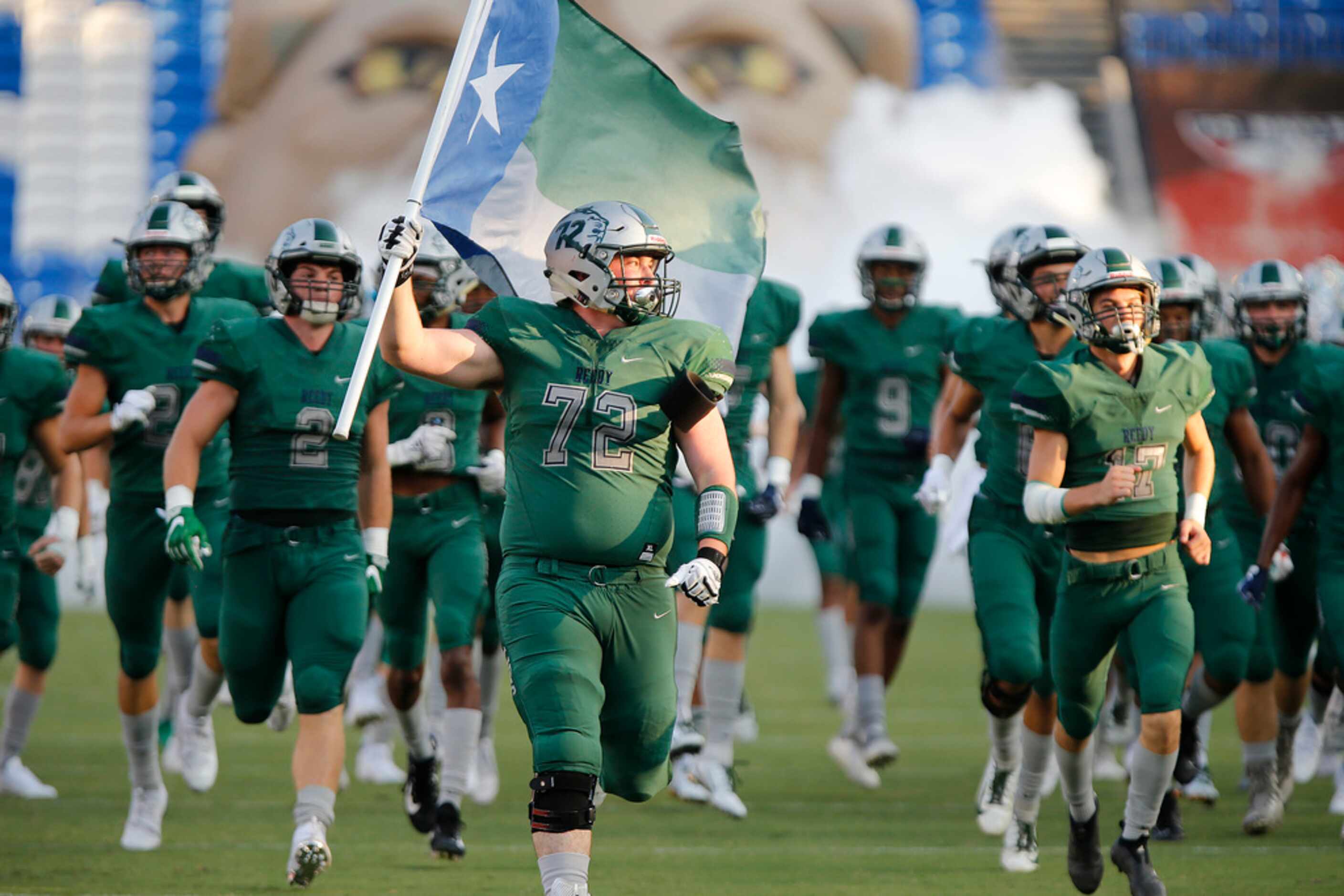 Reedy High School offensive lineman Ethan Baker (72) carries a flag onto the field before...
