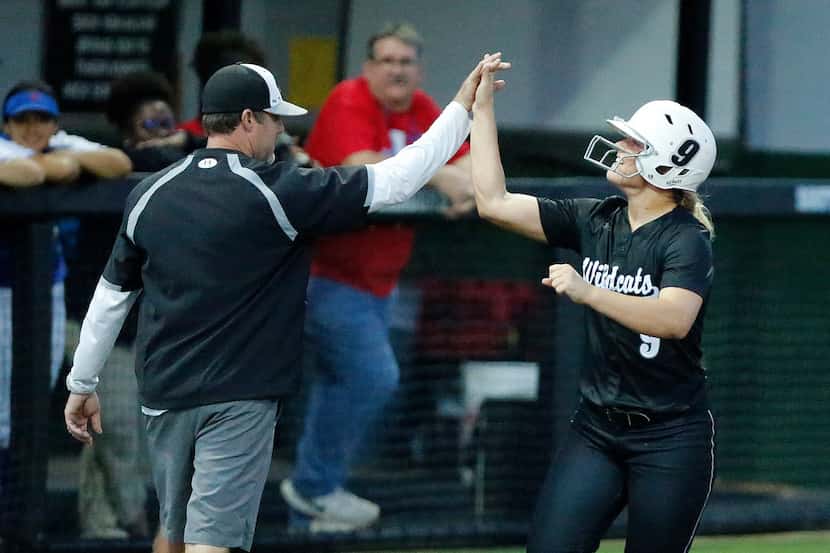 Denton Guyer's Maddy Holder high-fives coach Keith Medford as she rounds third base after...