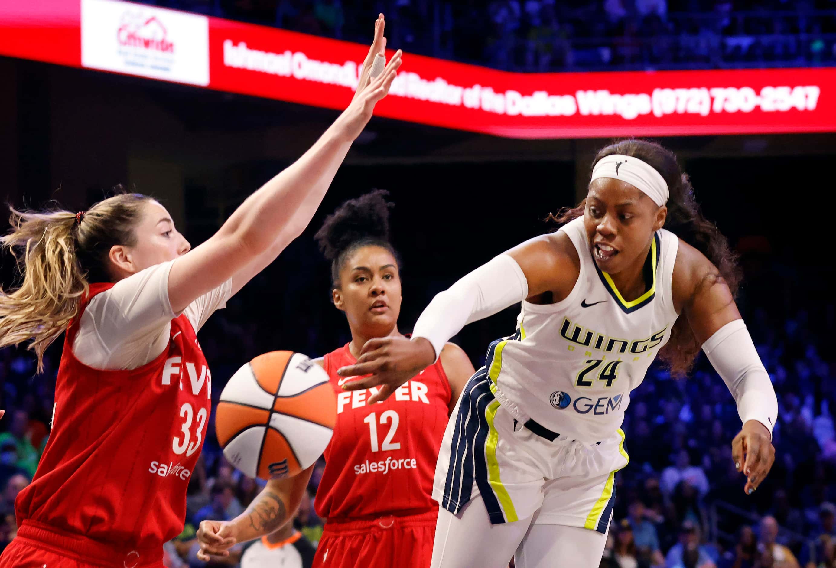 Dallas Wings guard Arike Ogunbowale (24) makes a flying bounce pass around Indiana Fever...
