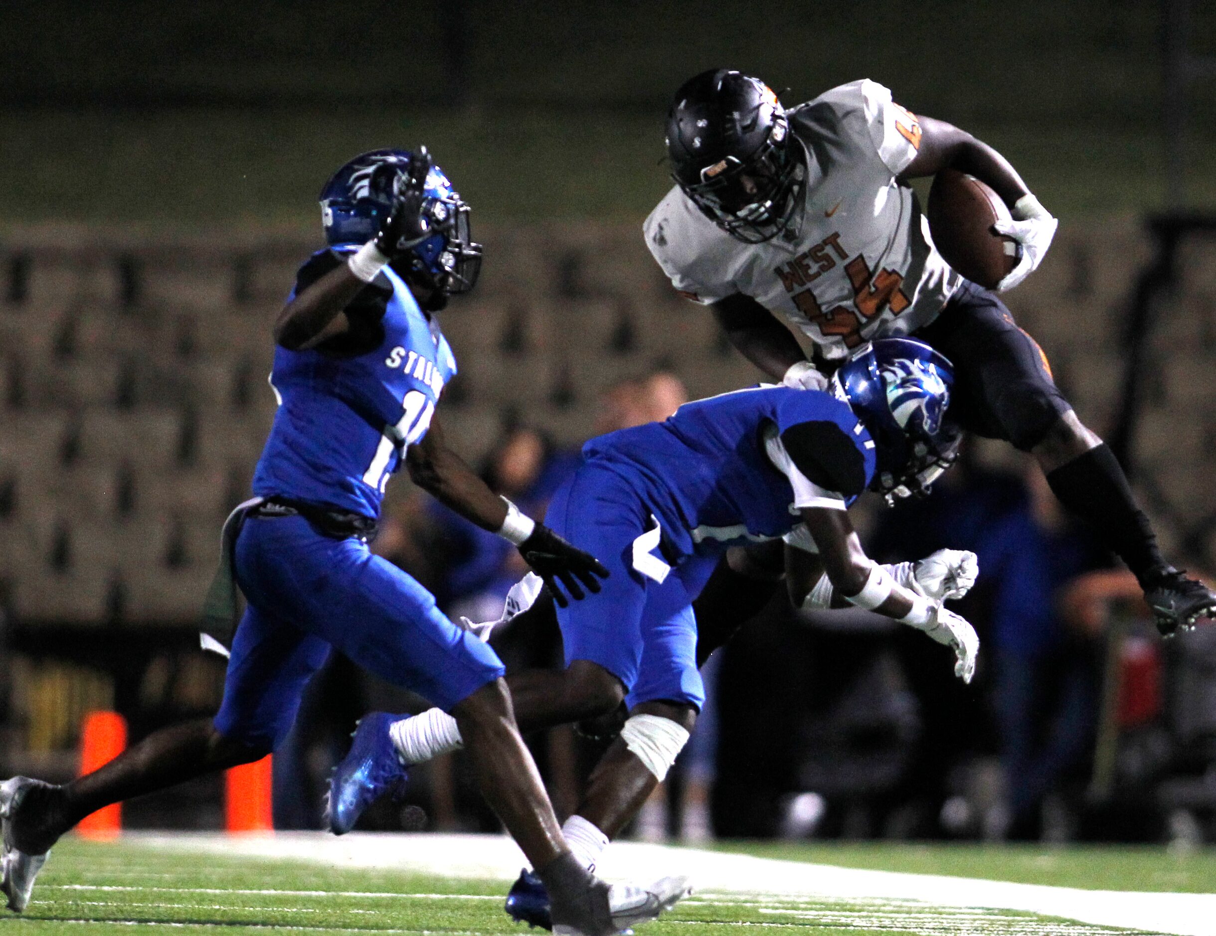 West Mesquite's Canaan Dirden (44) is knocked off his feet by North Mesquite defensive back...