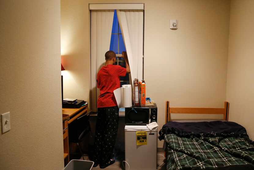 Jaylon Miller cracks his window for a breath of fresh air in his dorm room at the University...