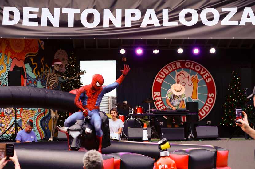 Denton Spiderman, Jeremy Sons, rides a mechanical bull at Dentonpalooza in Denton on Friday,...