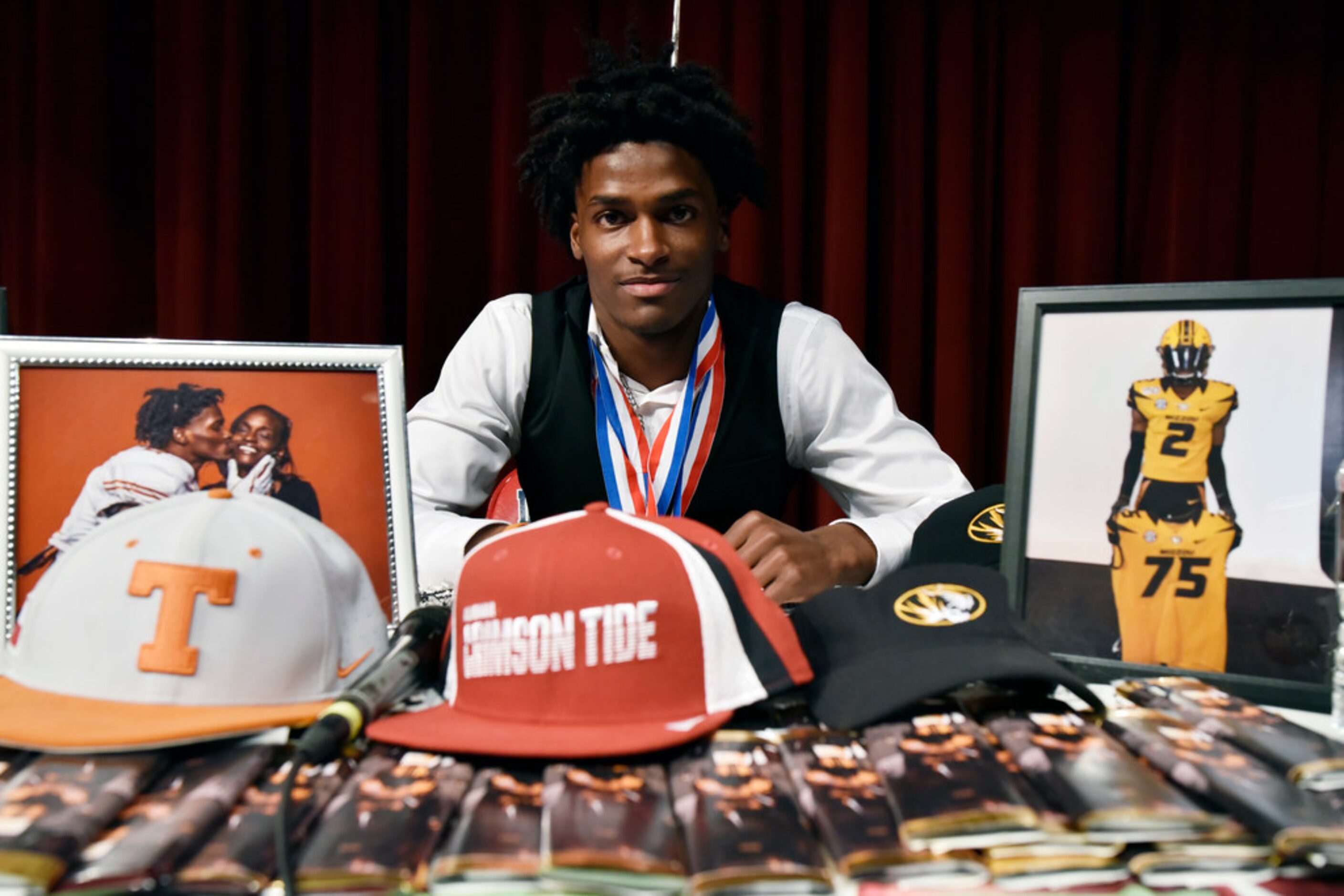 Duncanville cornerback Ennis Rakestraw, Jr., sits at his signing table with three university...