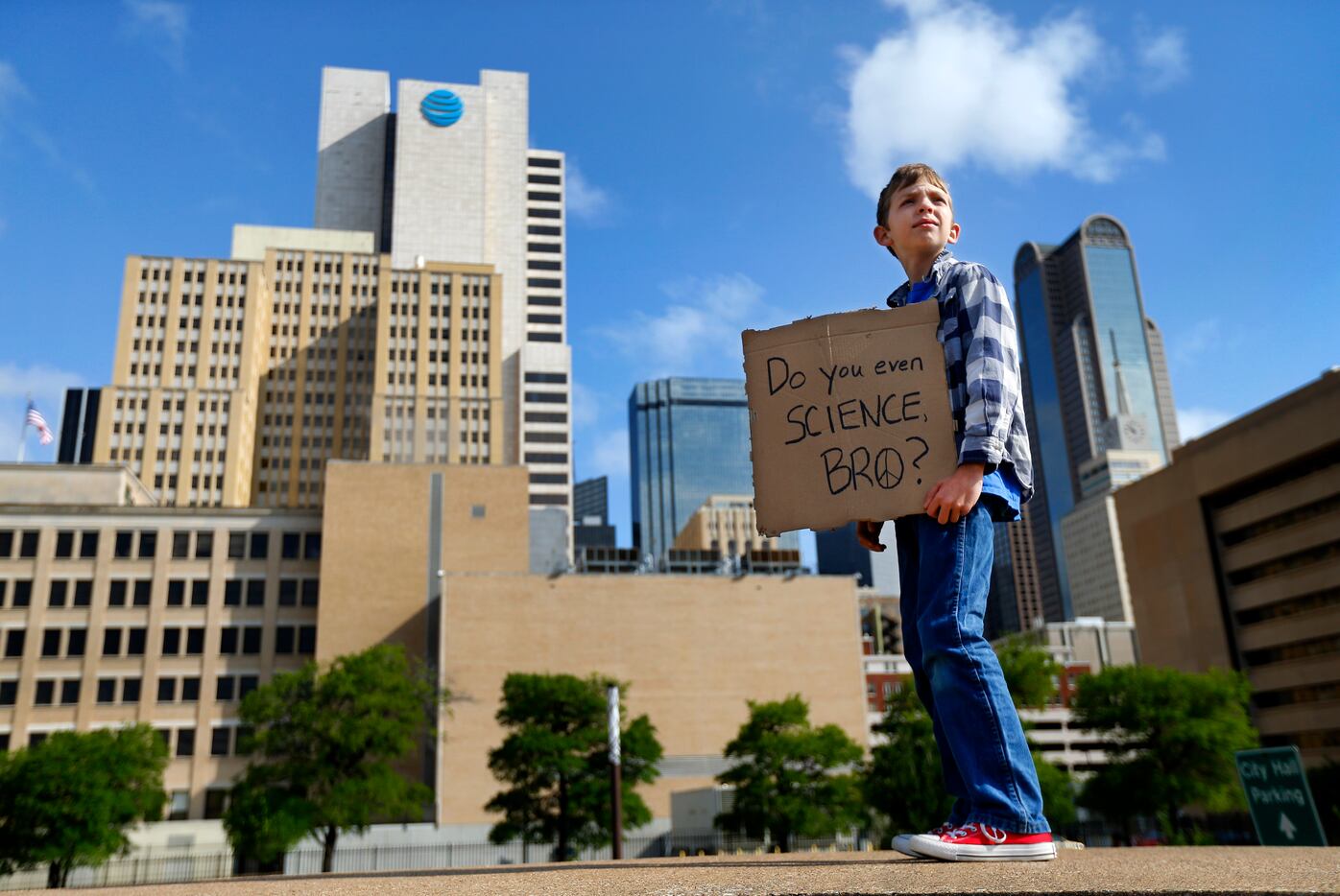 Martin Thomas, 10, of Dallas carries his homemade, pizza box sign as people gathered in...