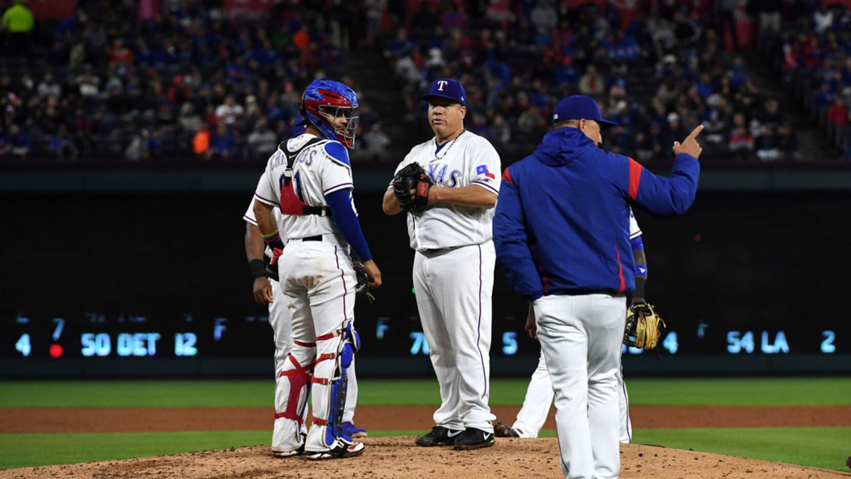 Texas Rangers starting pitcher Bartolo Colon, center, stands on the mound with catcher...