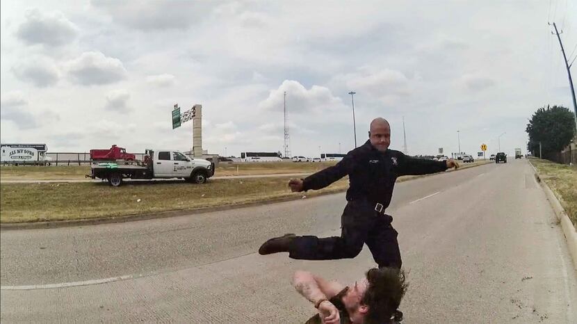A frame from a police body camera shows Dallas firefighter Brad Cox kicking Kyle Robert Vess...