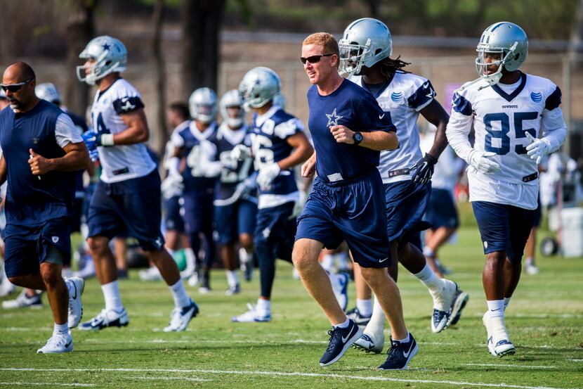 Dallas Cowboys head coach Jason Garrett runs with his team between drills during the first...