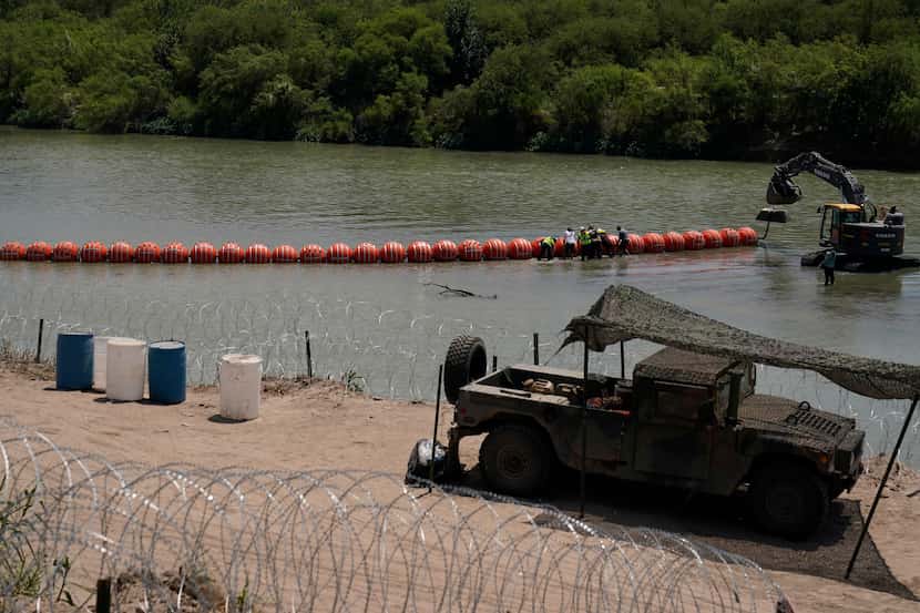 Workers assemble a floating border barrier in the Rio Grande in Eagle Pass, Texas, on, July...