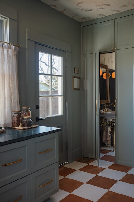 Utility room with sage green cabinetry