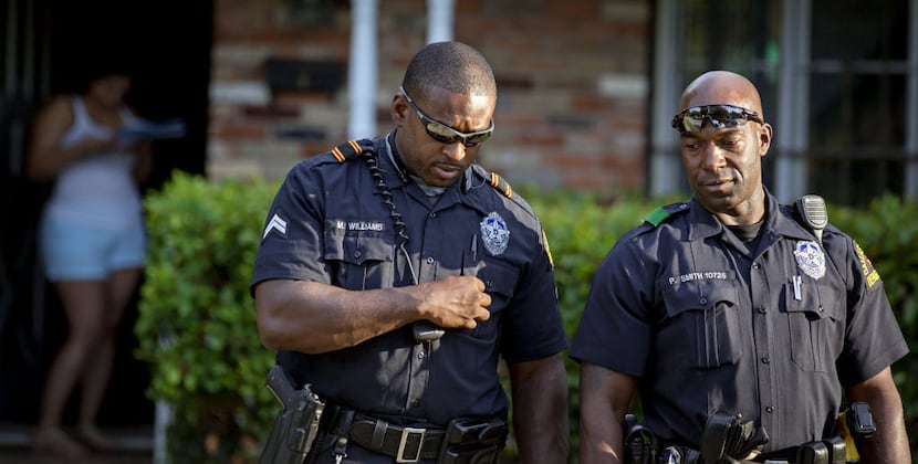 Dallas police Sr. Cpl. Melvin Williams (left) and Officer Paul Smith walk to their squad...