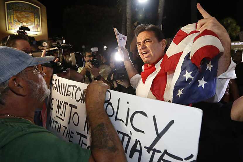 Peter Bell (right) argues with demonstrators prostesting President Barack Obama's decisions...