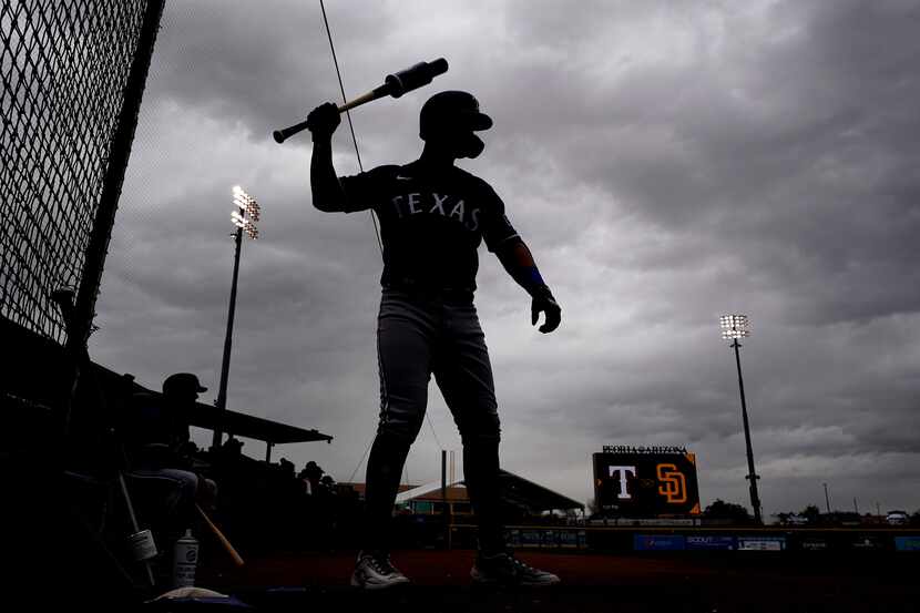 Texas Rangers' Mark Mathias warms up on deck before a spring training baseball game against...