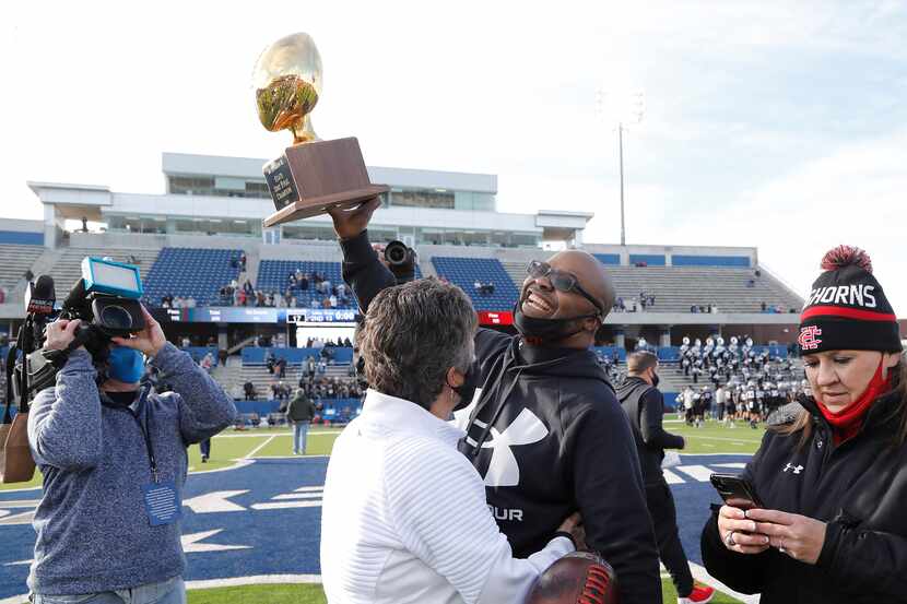 Cedar Hill High School head coach Carlos Lynn hoists the trophy after the win as Denton...