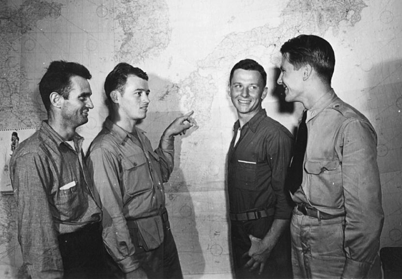 Survivors Joe Barta, Mac McDole, and Doug Bogue indicate Palawan on a map to an intelligence...