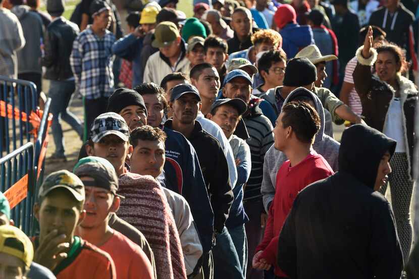 Central American migrants, most from Honduras, lined up Tuesday to receive their breakfast...