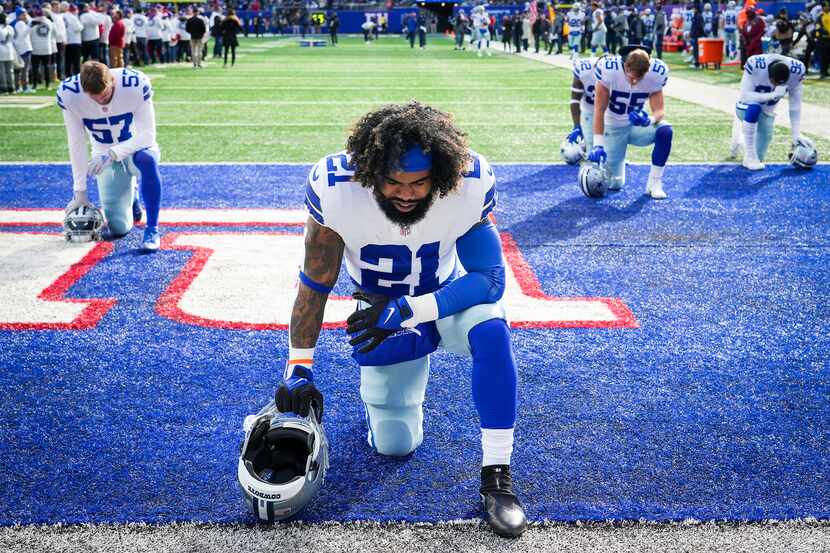 Dallas Cowboys running back Ezekiel Elliott knees on the field before the first half of an...