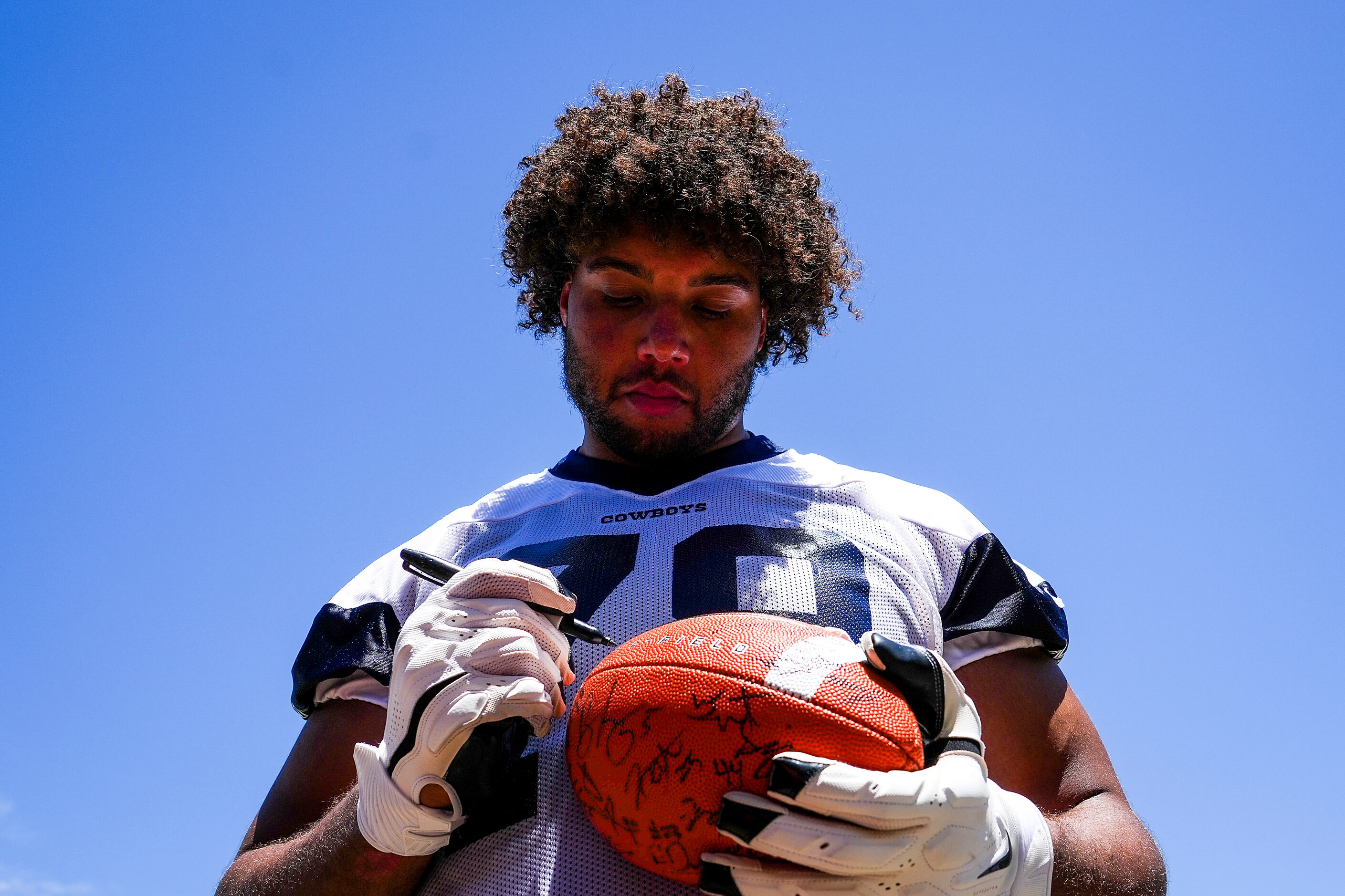 Dallas Cowboys offensive lineman Terence Steele autographs a football following the first...