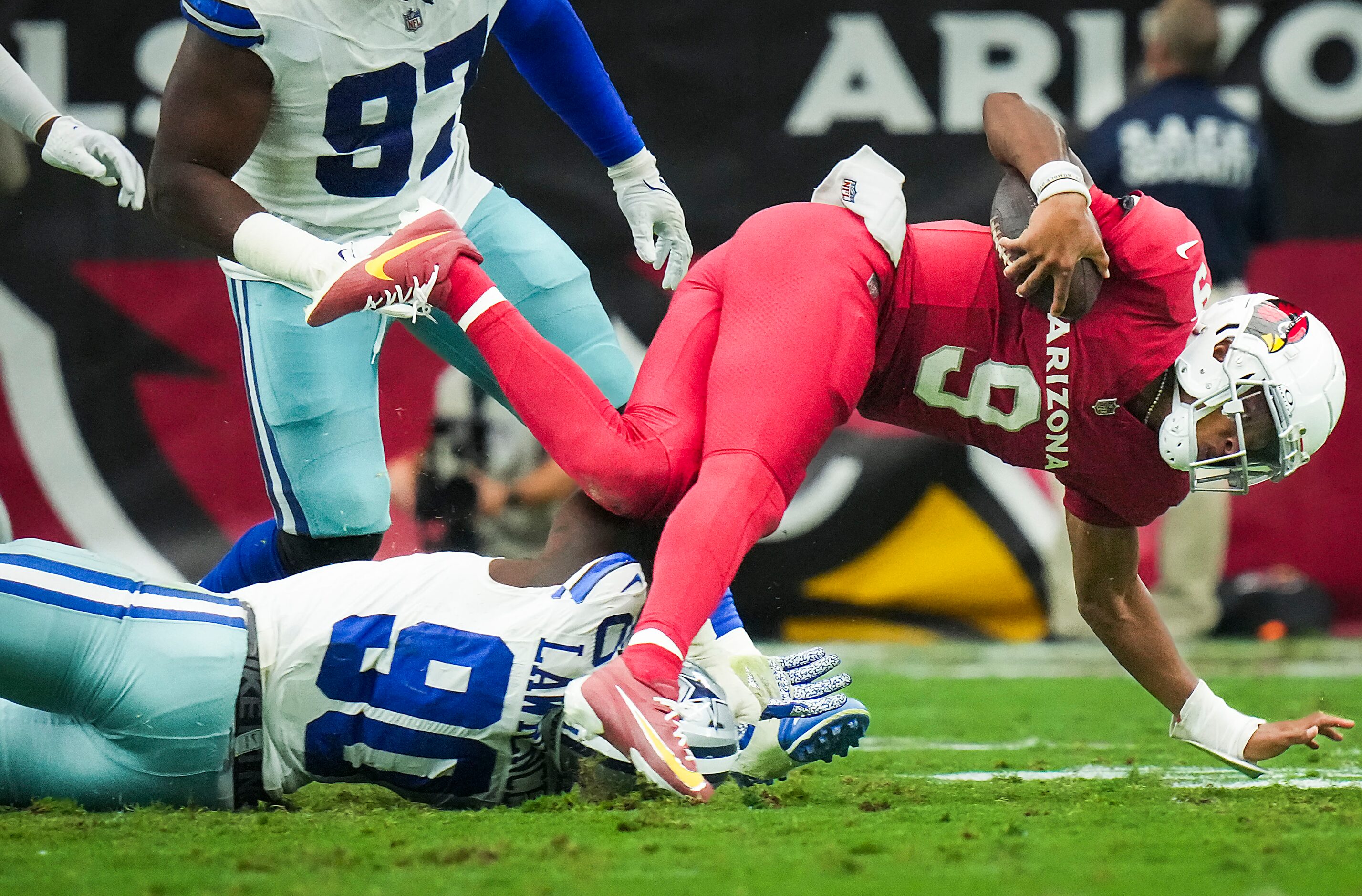 Arizona Cardinals quarterback Joshua Dobbs (9) is tripped up by Dallas Cowboys defensive end...