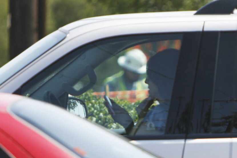 A woman uses her mobile phone while stopped at Collins Road and Interstate 30 in Arlington....