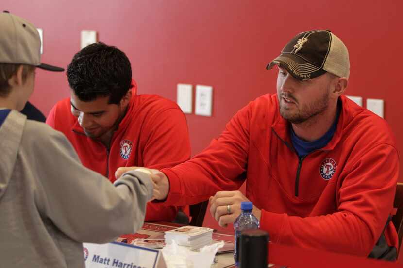 Texas Rangers pitcher Matt Harrison hands back an autographed baseball to Chase Wernimont,...