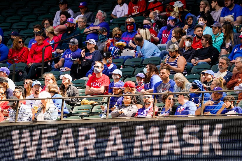 Signs encourage fans to wear face coverings during a game between the Texas Rangers and the...