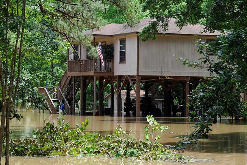 A house built on tall piers is surrounded by flood water from the San Jacinto River Thursday...