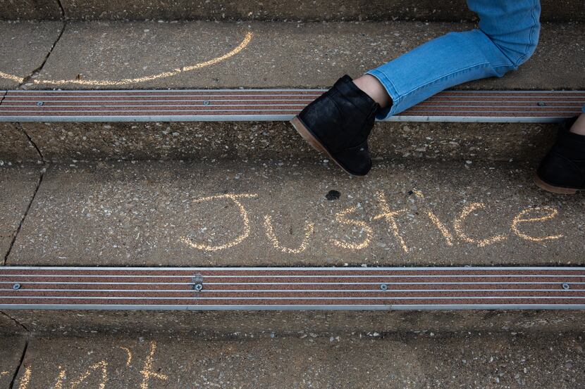 Demonstrators write with chalk on the stairs leading up to the Collin County Courthouse...
