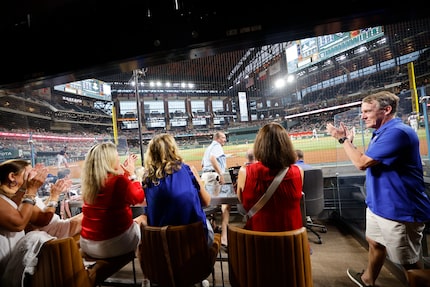 Scott Maslowski, senior vice president of sales at Daltile, right, watches a baseball game...