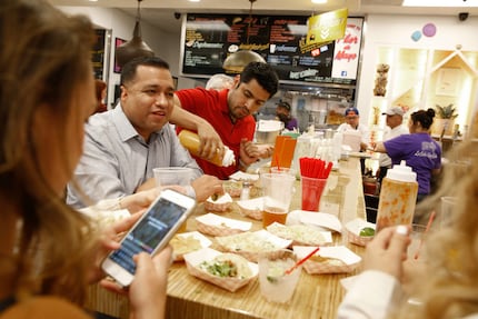 Edgar Vasquez (center) and Raul Santillan (left) eat at Salsa Limon in Dallas on March 16,...