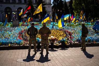 Ukrainian service men stand next to Ukrainian flags and photographs placed in memory of...
