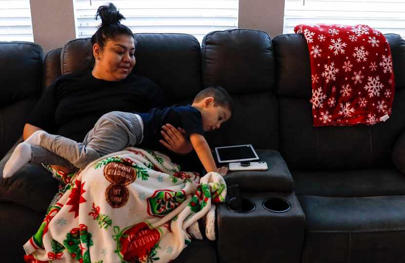 Noah Fabian, 3, and his mother, Gloria Vigil, look at an iPad while on the couch together at...