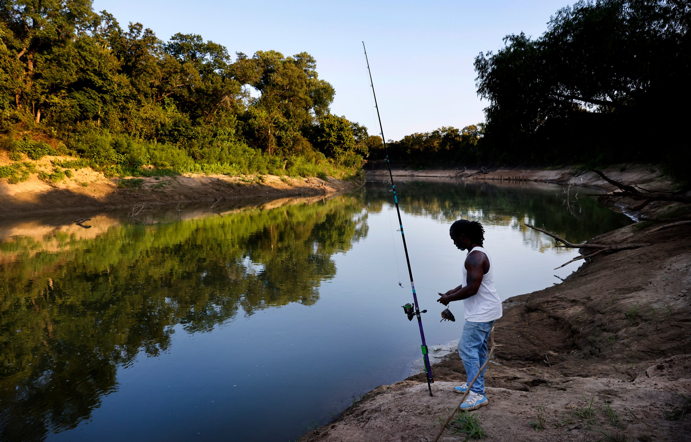 As the sun fades on the Trinity River, Odell Allen attaches a carp head to his hook as he...