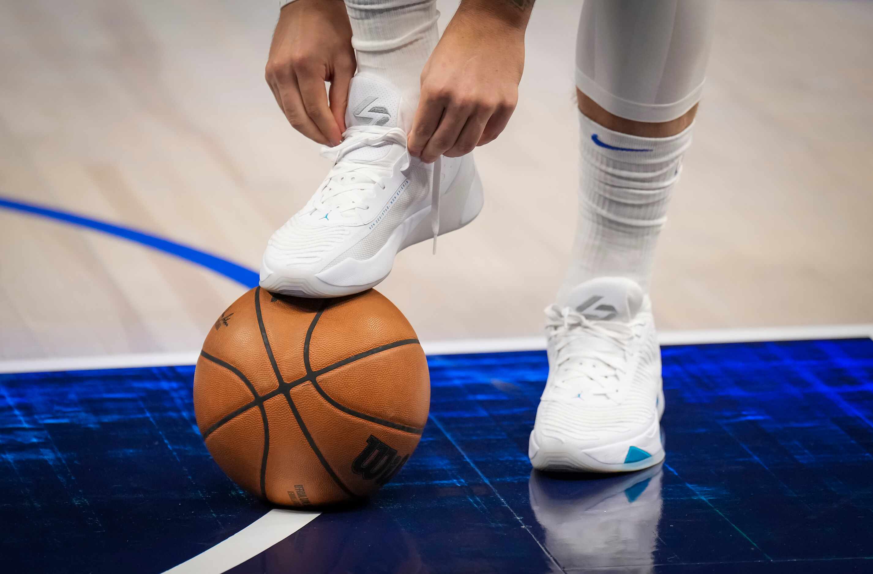 Dallas Mavericks guard Luka Doncic ties his shoes as he takes the court to warm up before an...