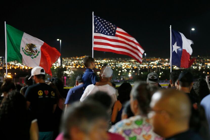 Flags wave in the wind as people gather at the site of a makeshift memorial for victims of...