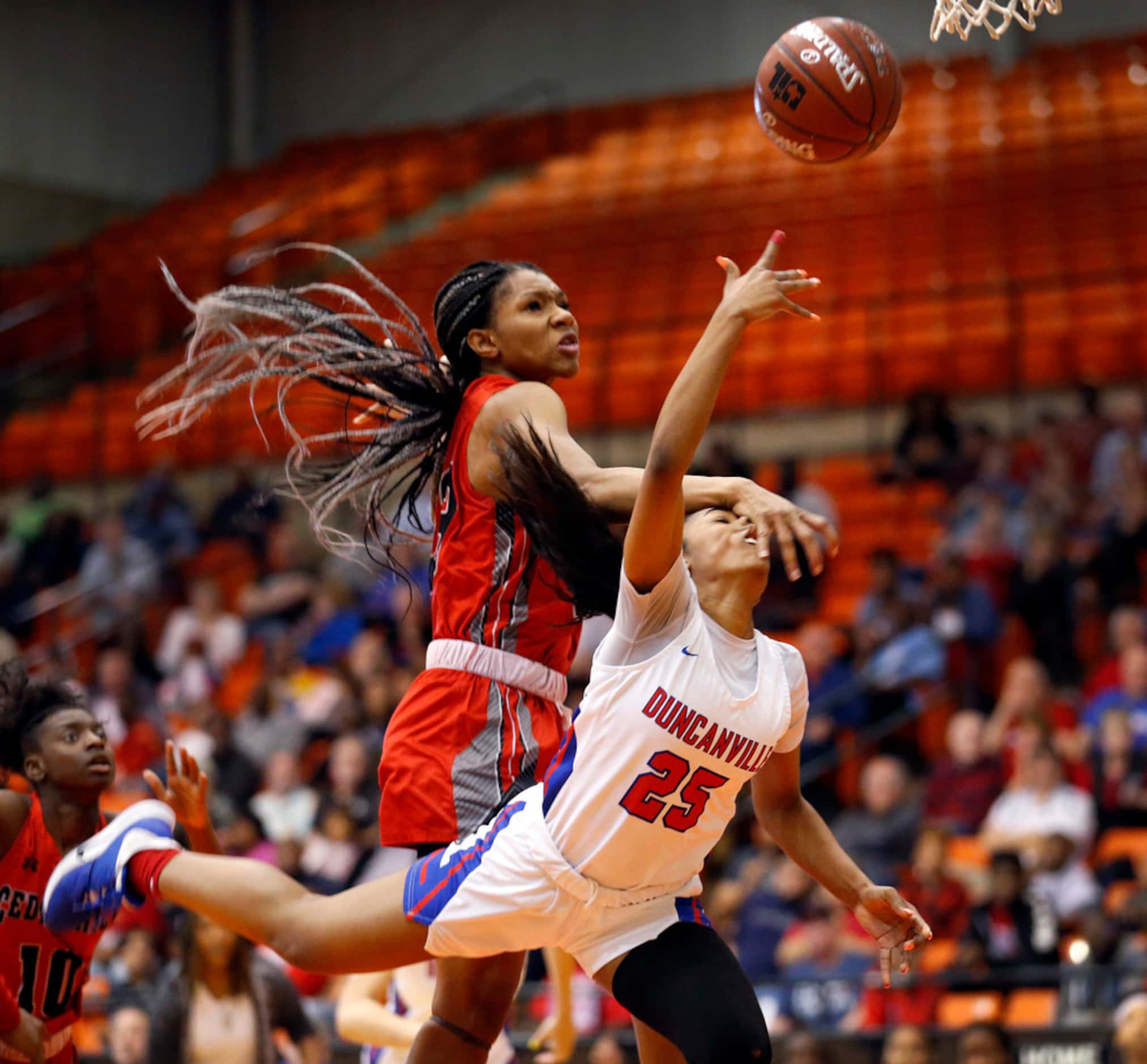 Duncanville's  Deja Kelly (25) is fouled by Cedar Hills' Anzhane' Hutton (23) as she lays up...