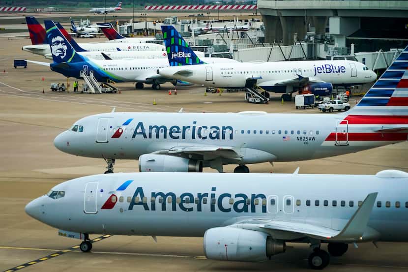 American Airlines planes taxi from gates at DFW International Airport as aircraft from...