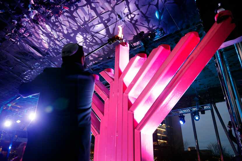 Boris Grinstein lights the shamash candle atop the pink menorah used annually in Klyde...