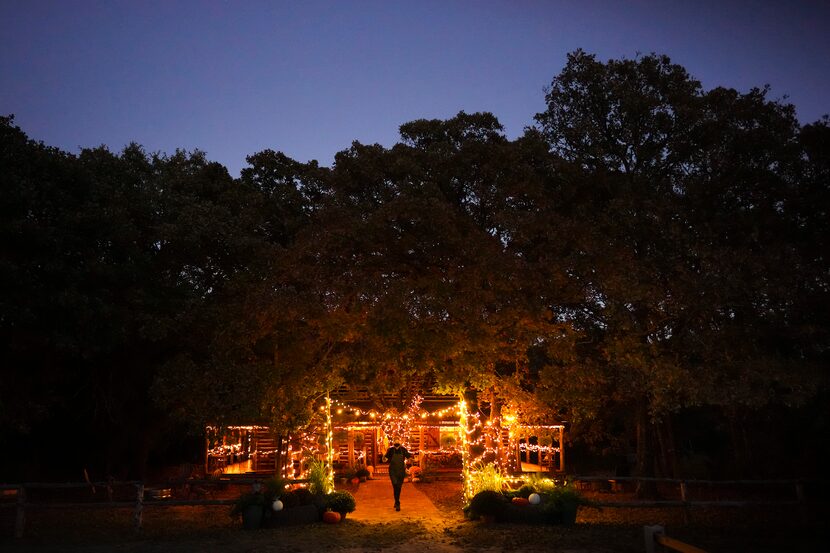 Chef Lisa Becklund waves from the front walk of the cabin where she hosts dinner as dusk...