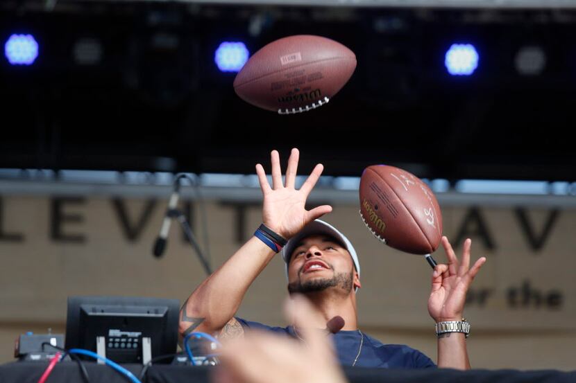 Dallas Cowboys quarterback Dak Prescott's tries to catch multiple footballs to sign during a...