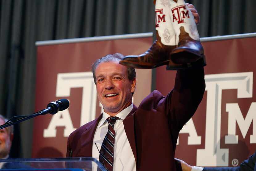 Texas A&M's new coach Jimbo Fisher shows of his new boots during a press conference at Kyle...