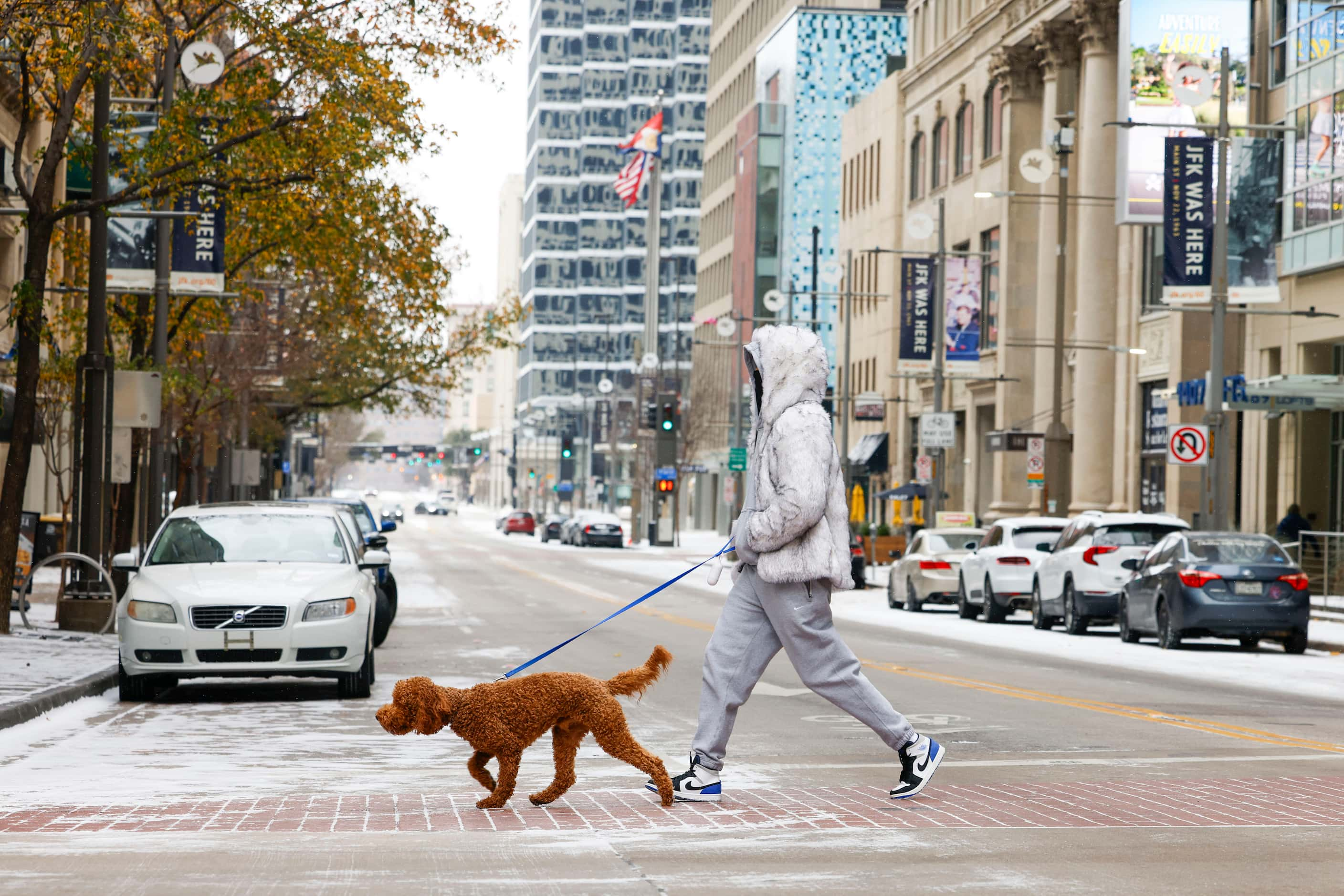 A pedestrian with their dog crosses snow covered Main St. on Monday, Jan. 15, 2024 in Dallas. 