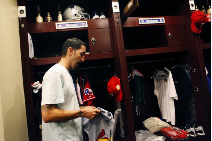 Texas Rangers' Mike Adams (37) folds up an autographed Pujols Cardinals jersey he received...