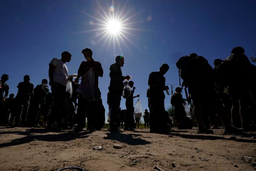 Migrants wait to be processed by the U.S. Customs and Border Patrol after they crossed the...