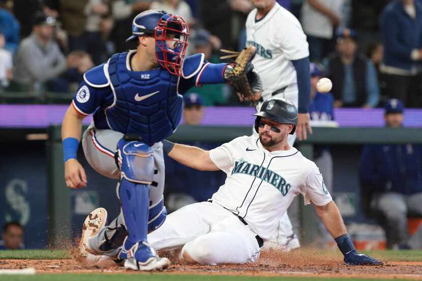 Seattle Mariners' Cal Raleigh, right, beats the throw to Texas Rangers catcher Andrew...
