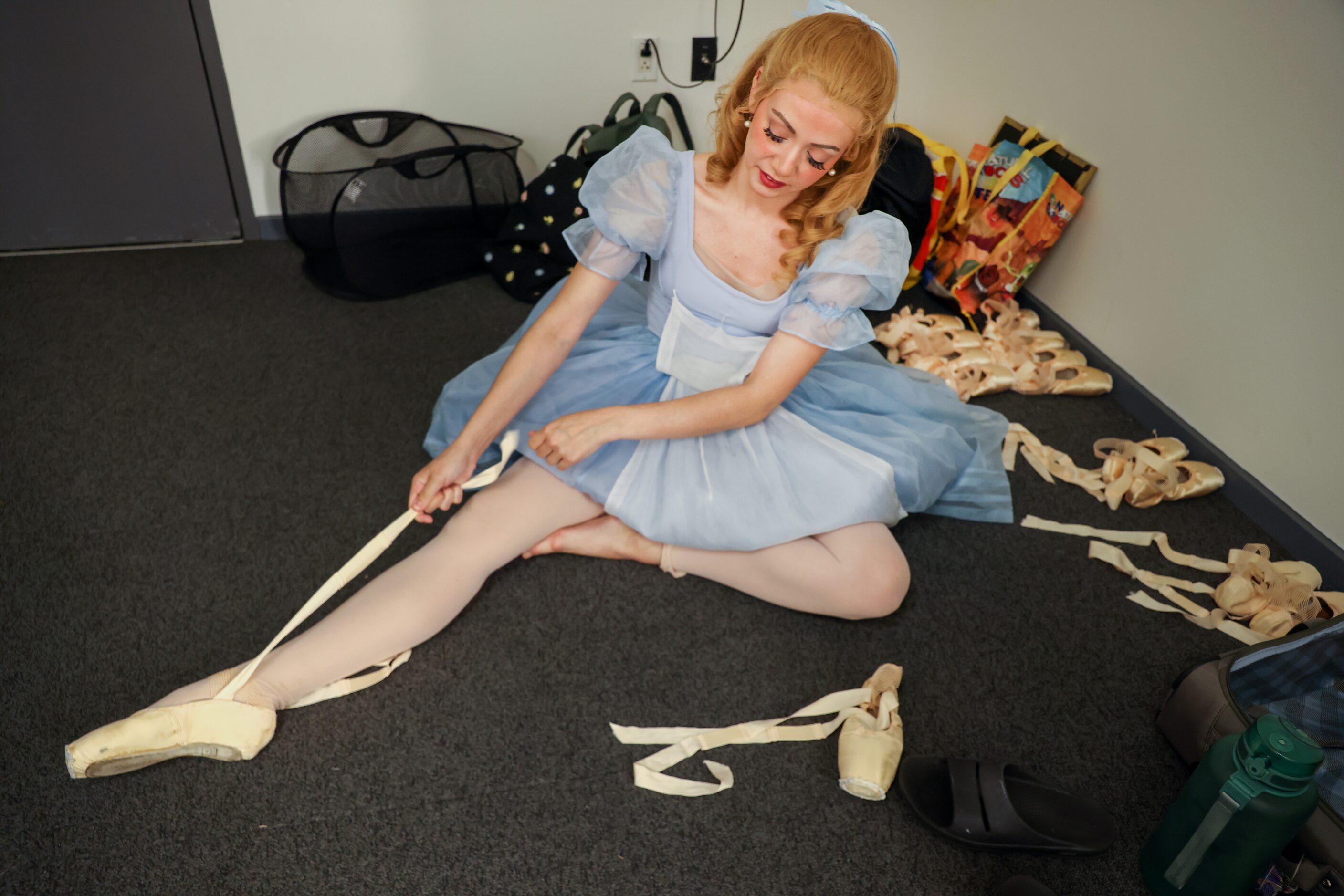 Alexandra F. Light pulls on the ribbons of her pointe shoes as she prepares for dress...