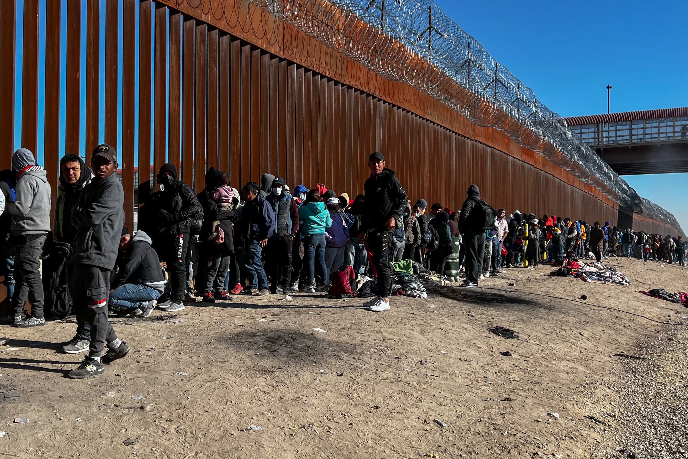 Migrants stand in line at a US-Mexico border gate from the banks of the Rio Grande River in...