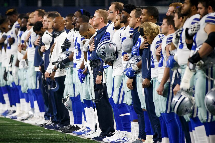 Dallas Cowboys players and coaches stand for the national anthem before an NFL football game...